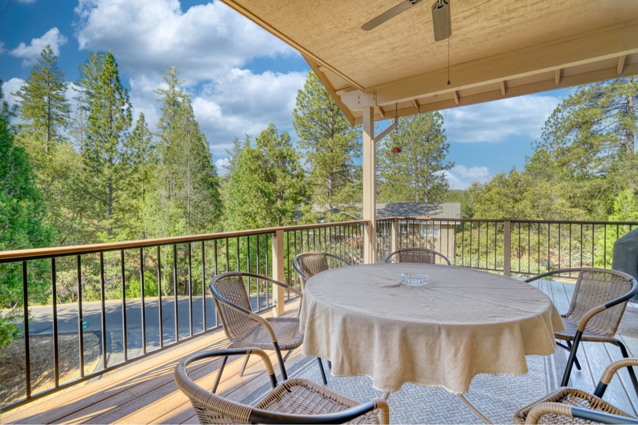 Covered deck dining table overlooking tall pines