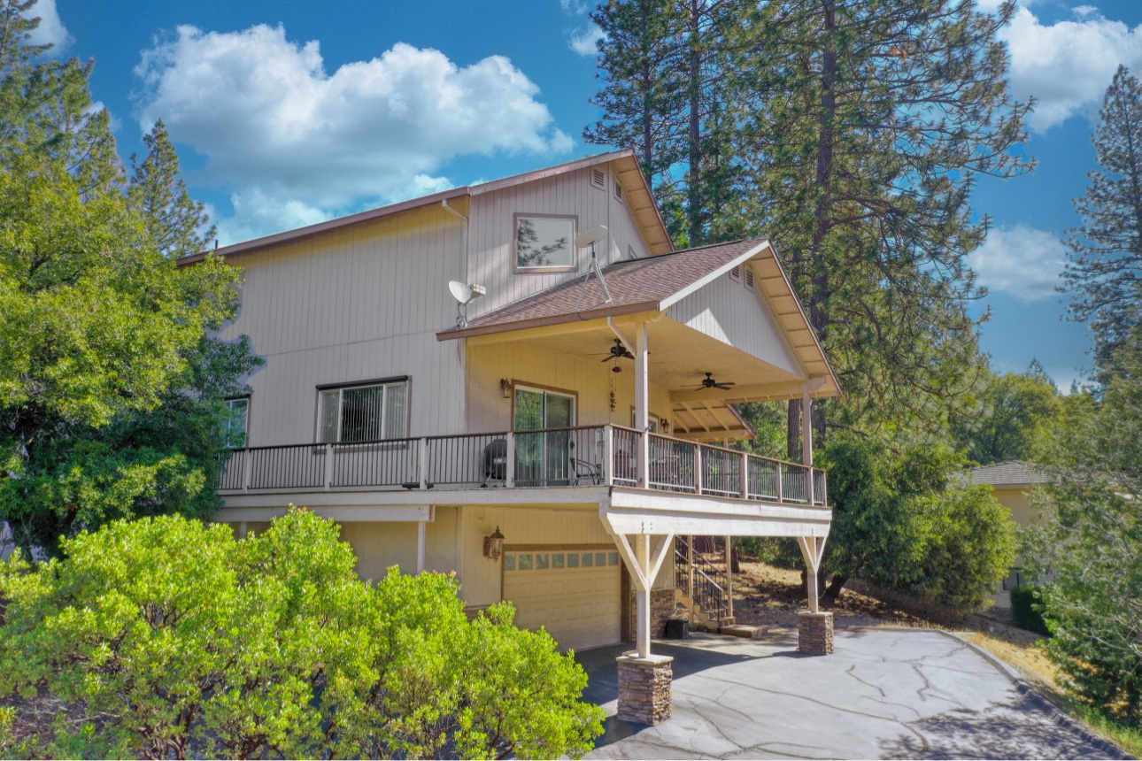 Front exterior of the cabin with covered deck, garage, and paved driveway