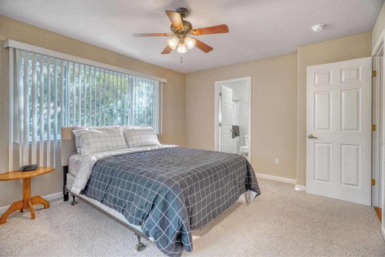 Bright queen bedroom with gray checked bedding and an ensuite bathroom