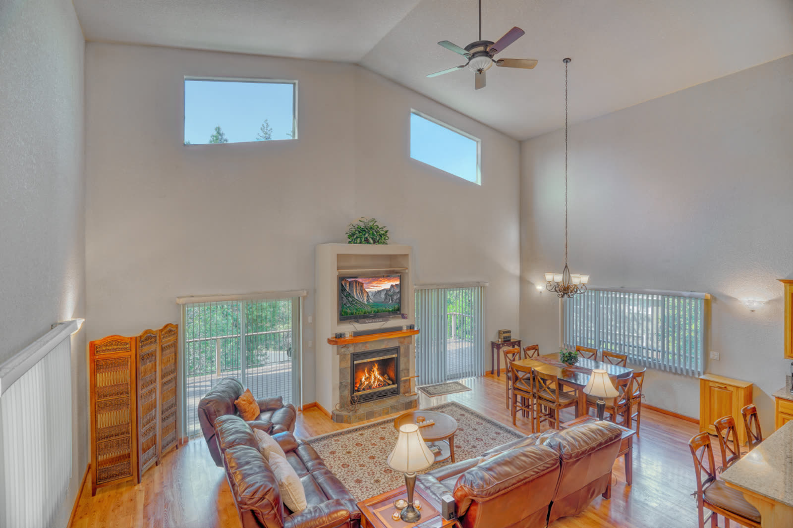 Vaulted Great Room with fireplace, dining area, and soaring windows