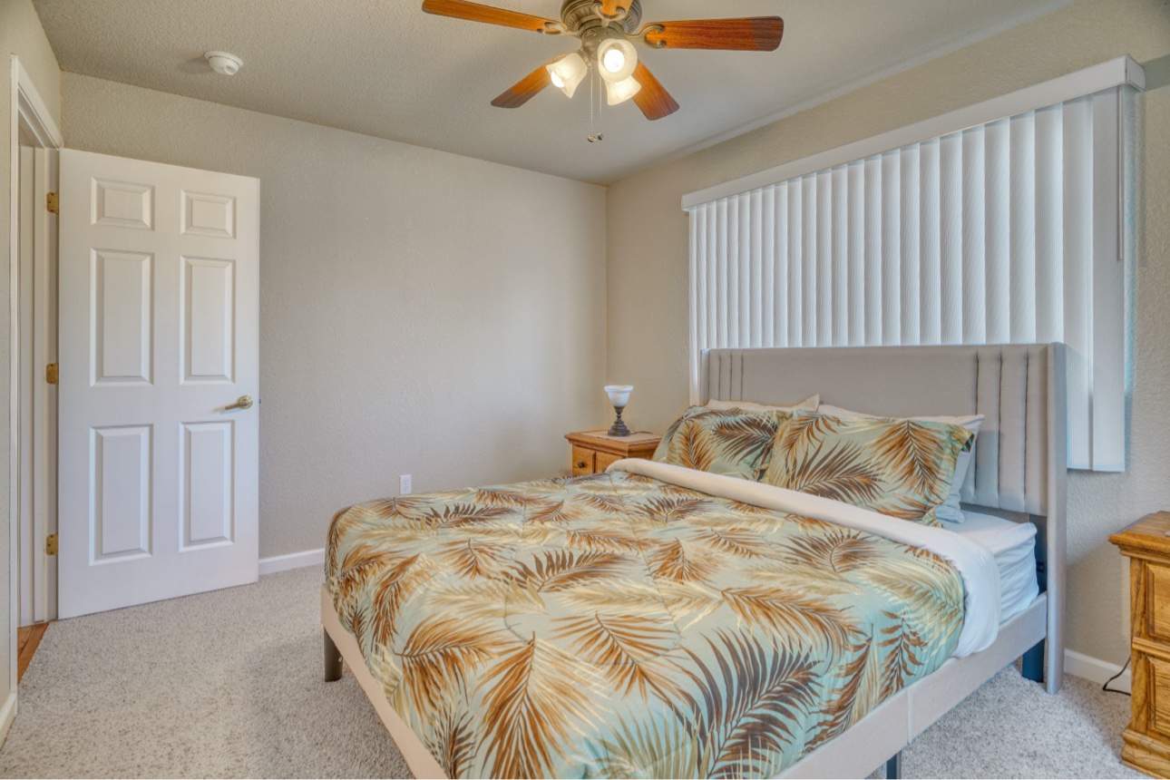 Queen bedroom with a softly upholstered headboard and leaf-patterned bedding