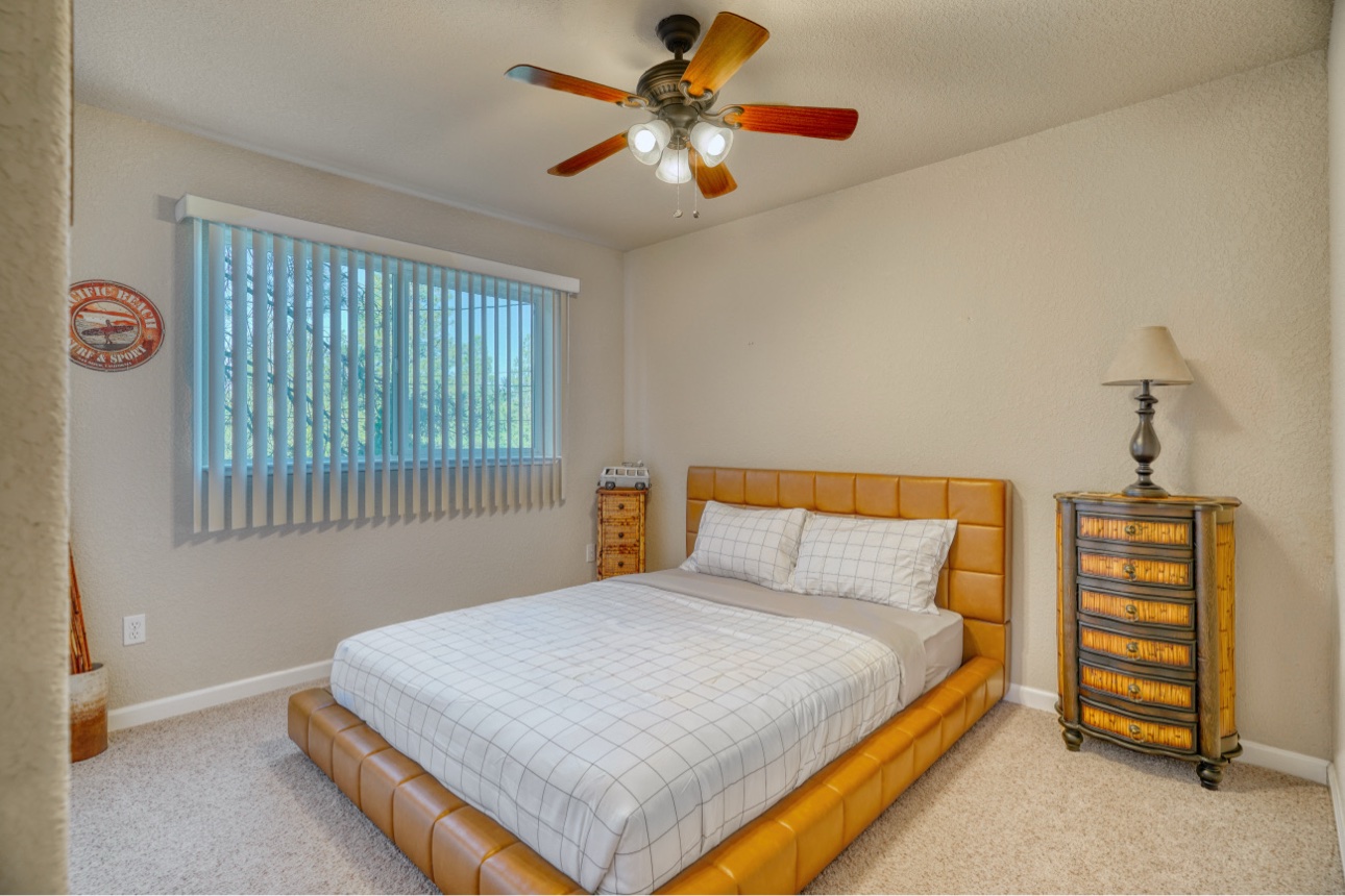 Queen bedroom with tan upholstered bed and woodland views